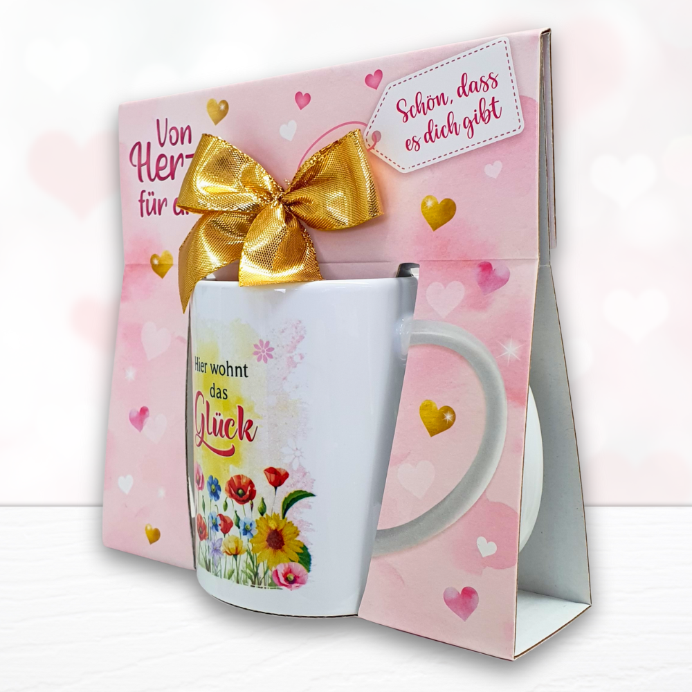 Kaffeetasse - Hier wohnt das Glück - Keramik Tasse mit Geschenkverpackung zum Geburtstag Muttertag Beidseitig mit rosa und roten Herzen bedruckt - schräg
